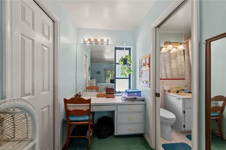 Vanity area with built-in desk, three-drawer storage, and a large mirror with overhead four-bulb lighting
