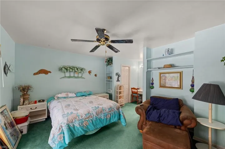 Spacious room featuring light blue walls, green carpeting, and a ceiling fan