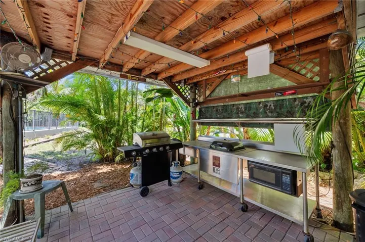 Covered outdoor kitchen featuring a wood-finish ceiling, brick paver flooring, and stainless steel counter space