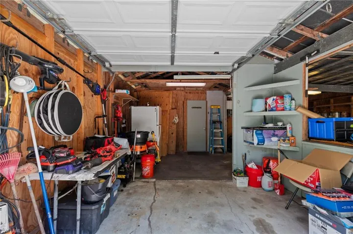 Attached garage with concrete flooring, wood paneling, and an overhead door