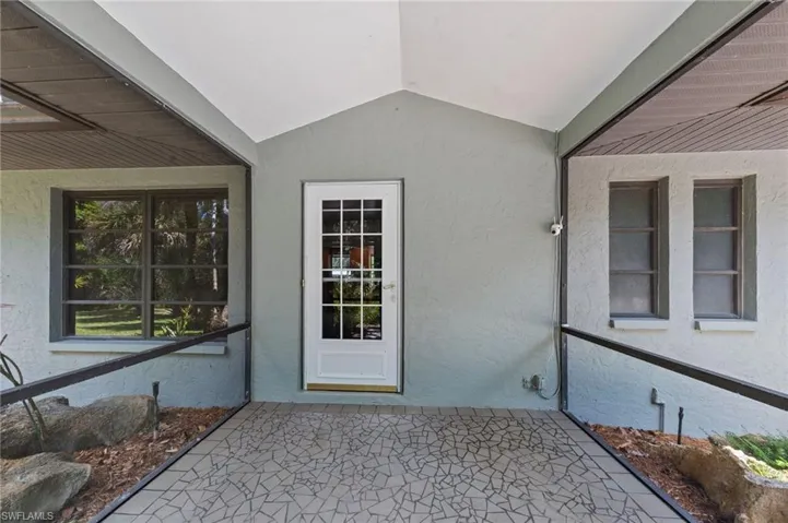 Covered patio area featuring a decorative tile floor and a white paneled glass door