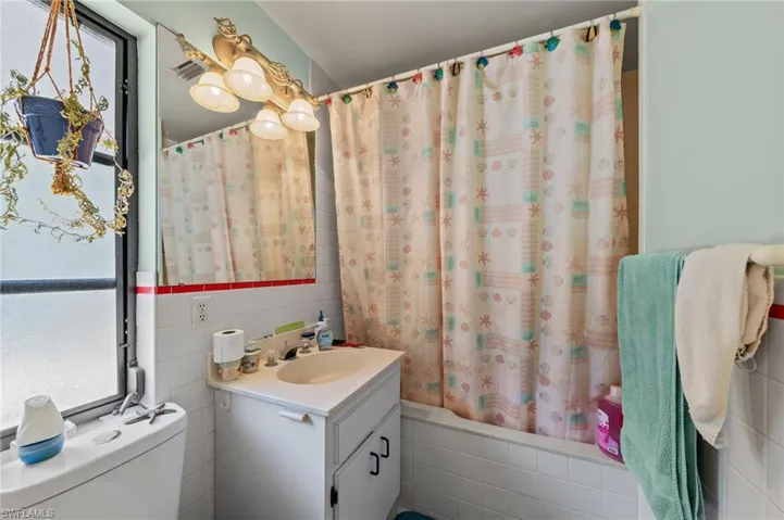 Bathroom featuring a vanity with a drop-in sink, a wall-mounted mirror, and a window with frosted glass