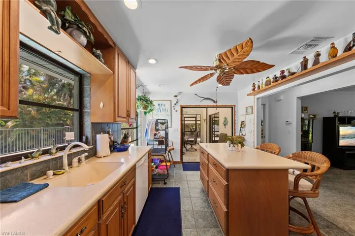 Kitchen featuring wood cabinetry, a center island with countertop seating, a double basin sink, and a multi-speed ceiling fan