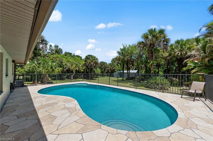 Freeform swimming pool with integrated steps, surrounded by a flagstone-style patio