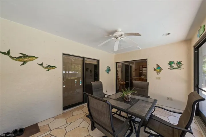 Covered patio featuring a ceiling fan, textured walls, and flagstone-style flooring