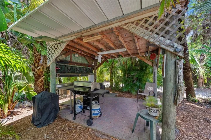 Covered outdoor pavilion with an aluminum roof and lattice detailing over a brick paver patio