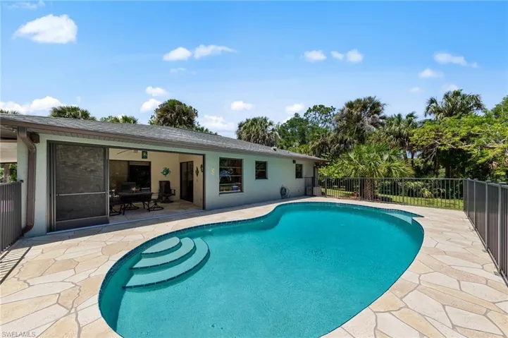 Freeform swimming pool featuring integrated steps and a surrounding flagstone patio