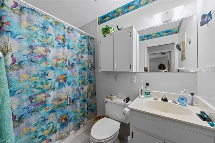 Bathroom featuring a single vanity with a laminate countertop, integrated sink, and white cabinetry