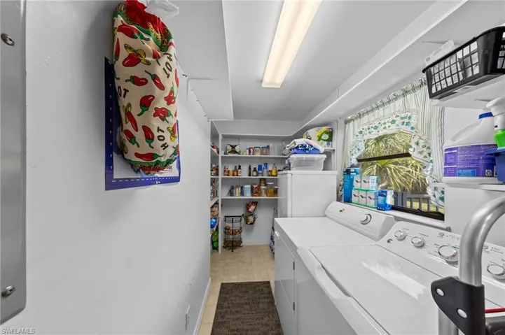 Dedicated utility room featuring a front-load washer and dryer set, fluorescent ceiling lighting, and a window with exterior landscaping visible