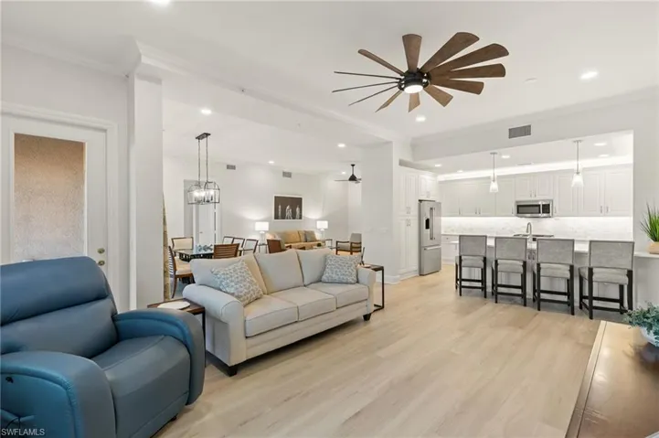 Living room featuring ornamental molding, light wood-style floors, a ceiling fan, and a chandelier