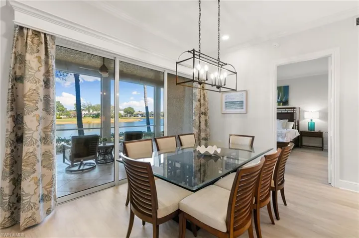 Dining area with hanging lights, light wood-style floors, and crown molding