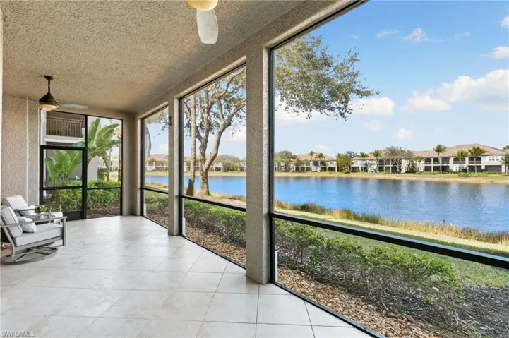 Unfurnished sunroom with a water view, tile patterned flooring, a textured wall, a textured ceiling, and a residential view