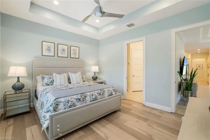 Bedroom with a tray ceiling, light hardwood / wood-style flooring, and ceiling fan