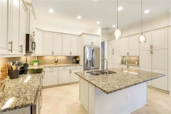 Kitchen featuring decorative backsplash, stainless steel appliances, a kitchen island with sink, and sink