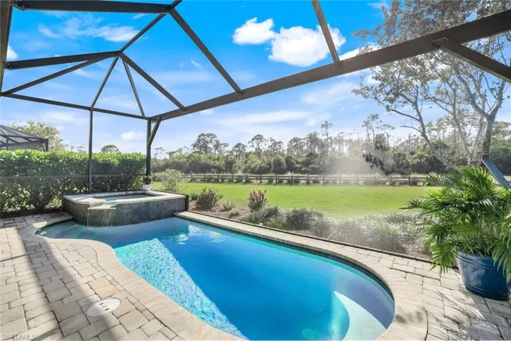 View of swimming pool featuring a lawn, an in ground hot tub, and a lanai