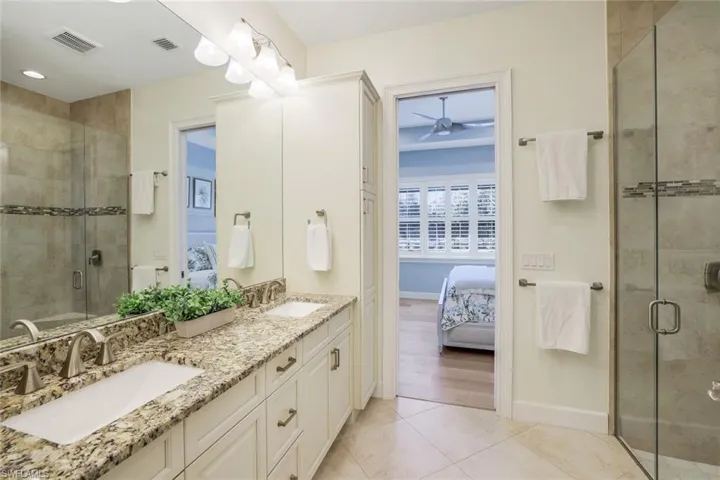 Bathroom featuring tile patterned flooring, vanity, and an enclosed shower