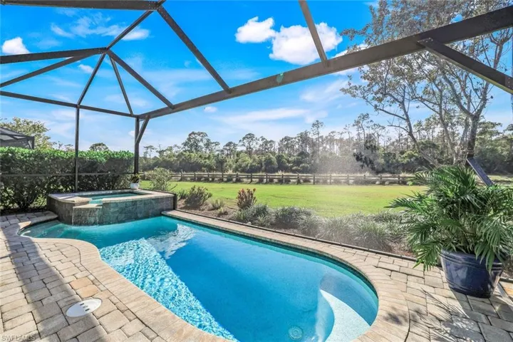 View of pool featuring glass enclosure, an in ground hot tub, and a yard