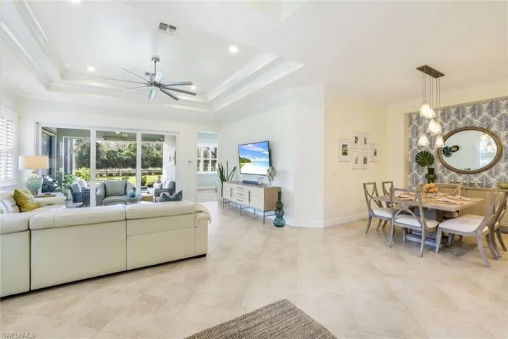 Living room featuring a raised ceiling, ceiling fan, and ornamental molding