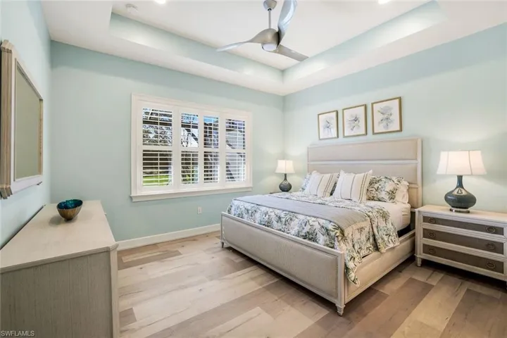 Bedroom with ceiling fan, light hardwood / wood-style floors, and a raised ceiling