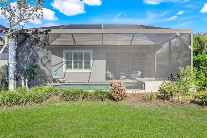 Rear view of house featuring a patio, glass enclosure, and a lawn