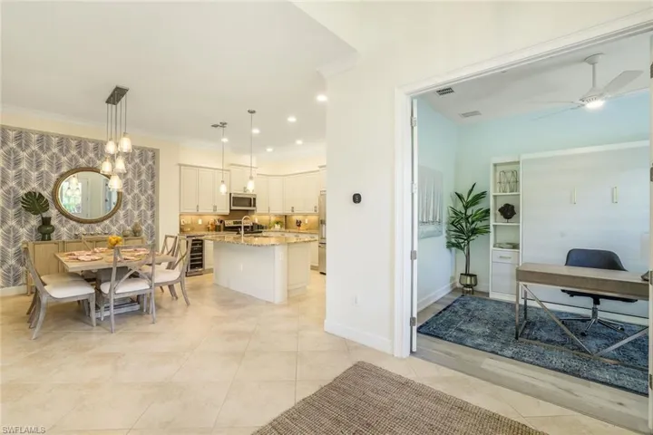 Tiled dining room featuring wine cooler, ceiling fan, ornamental molding, and sink