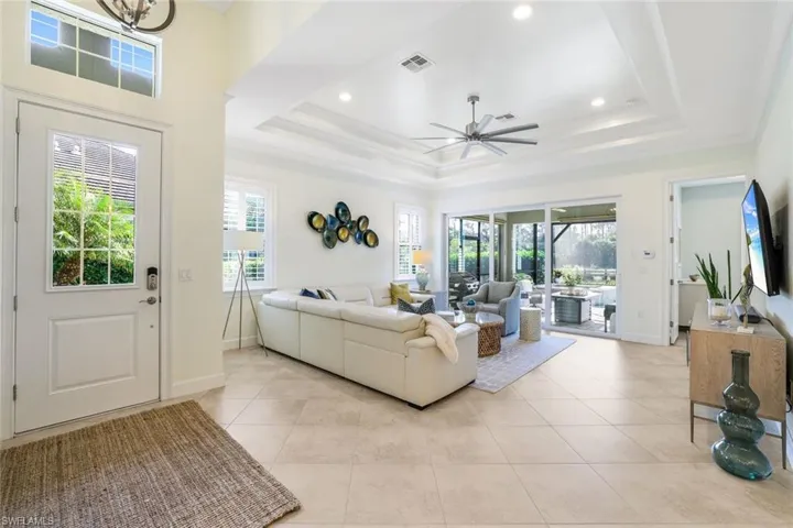 Tiled living room featuring ceiling fan, crown molding, and a tray ceiling
