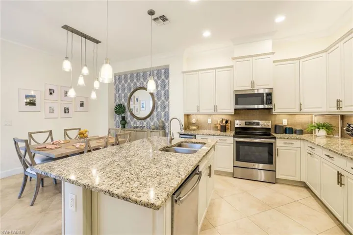 Kitchen with a kitchen island with sink, hanging light fixtures, stainless steel appliances, and sink