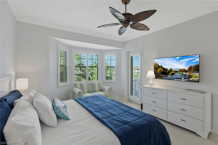 Spacious primary suite featuring high ceilings, a comfortable seating area, peaceful water views, and private access to the screened lanai.