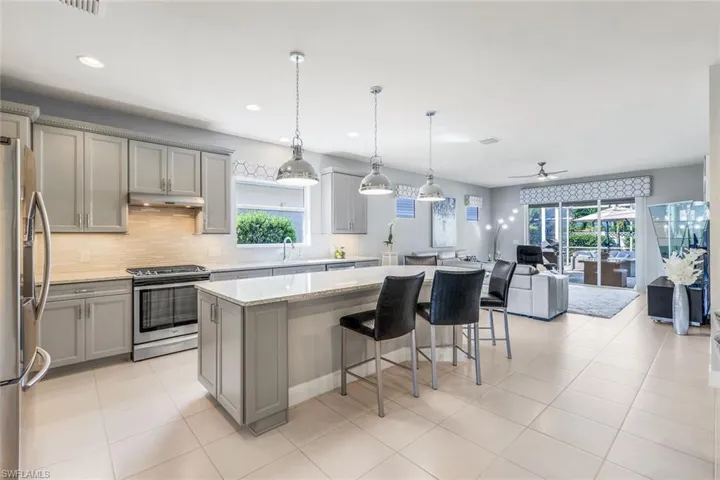 Kitchen with light tile patterned flooring, a kitchen island, ceiling fan, stainless steel appliances, and gray cabinets