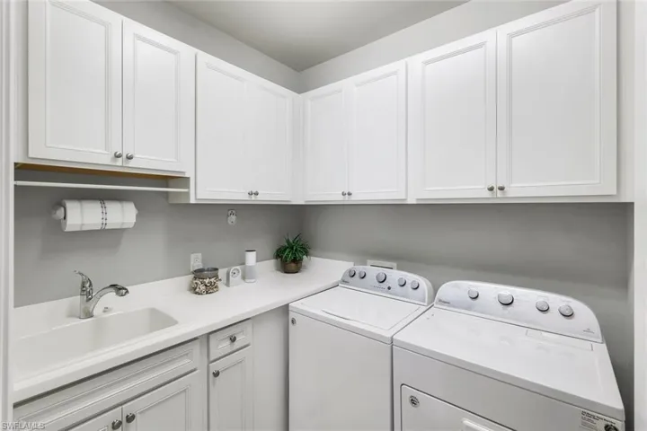 Laundry area with washing machine and dryer, sink, and cabinets