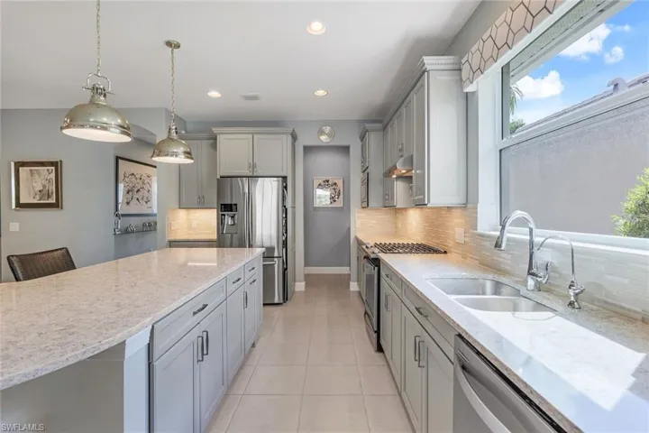 Kitchen with sink, appliances with stainless steel finishes, tasteful backsplash, light tile patterned floors, and gray cabinets