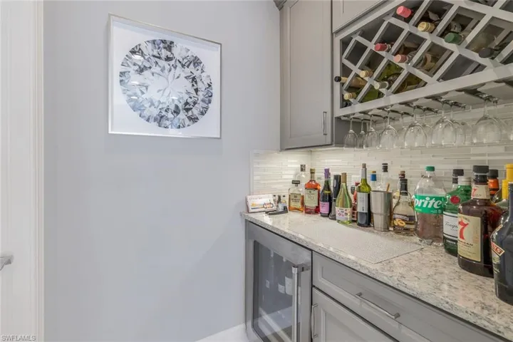 Bar with backsplash, wine cooler, and gray cabinetry