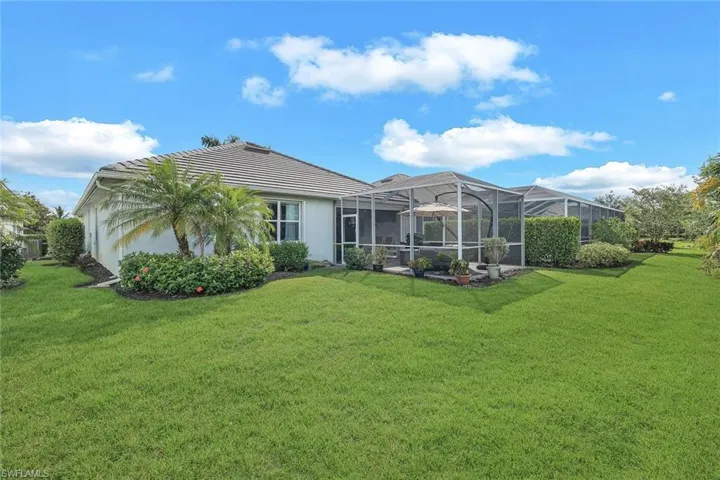 Rear view of house featuring a lawn and a lanai