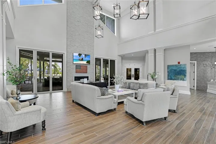 Living room with a wealth of natural light, a stone fireplace, and a towering ceiling
