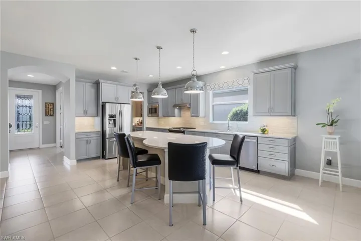 Kitchen featuring stainless steel appliances, tasteful backsplash, gray cabinetry, light tile patterned floors, and a kitchen island