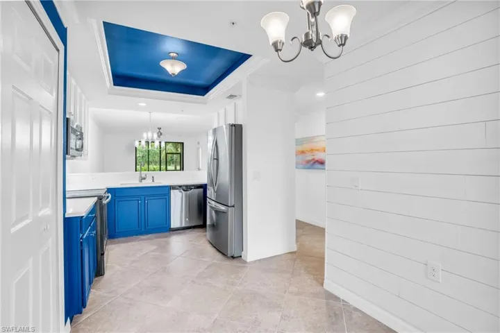 Kitchen with light tile patterned floors, stainless steel appliances, blue cabinets, hanging light fixtures, and sink