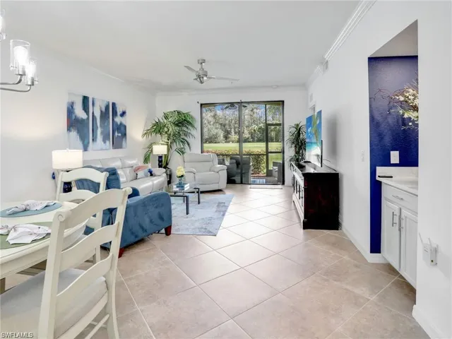 Tiled living room featuring crown molding and ceiling fan with notable chandelier