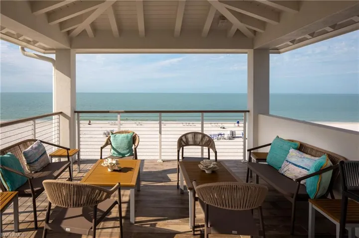 Balcony featuring view of water and beach and an outdoor living space