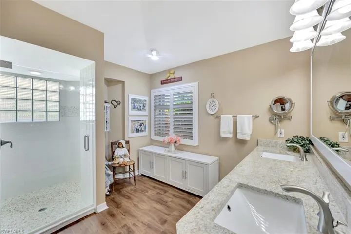 Full bathroom with a sink, double vanity, a shower stall, and wood finished floors
