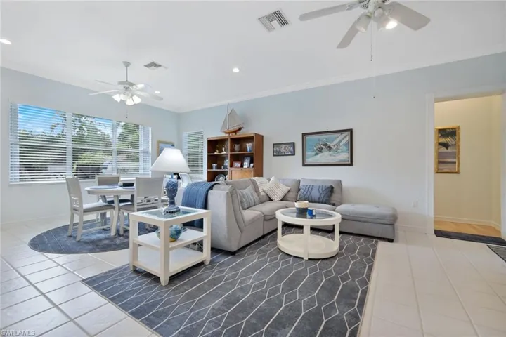 Tiled living room with crown molding and ceiling fan