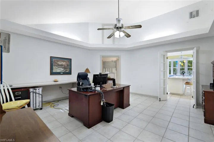 Tiled home office featuring a raised ceiling and ceiling fan