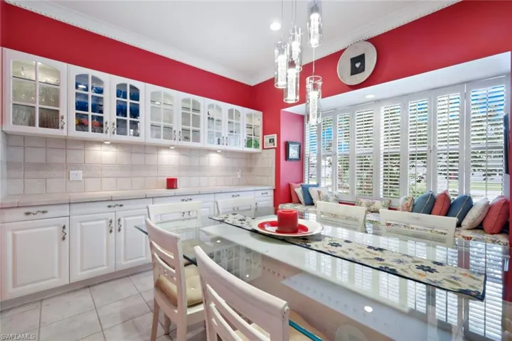 Kitchen featuring a notable chandelier, white cabinetry, pendant lighting, light tile patterned floors, and backsplash