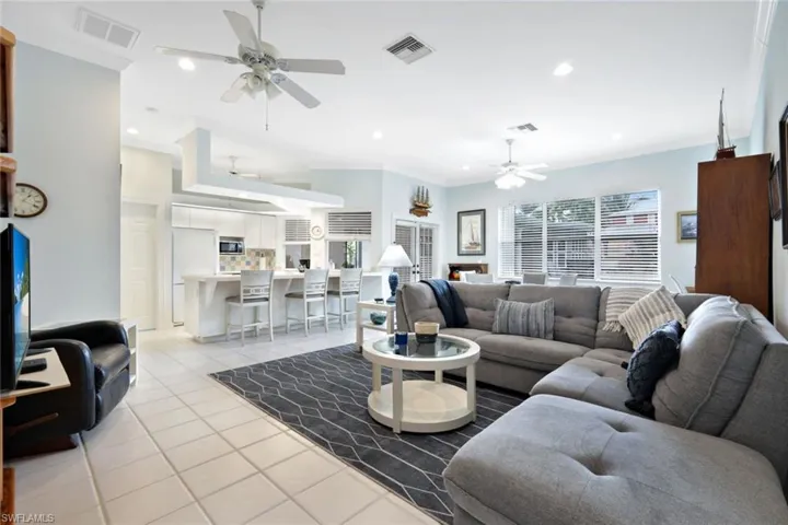 Living room featuring light tile patterned flooring, plenty of natural light, ornamental molding, and ceiling fan