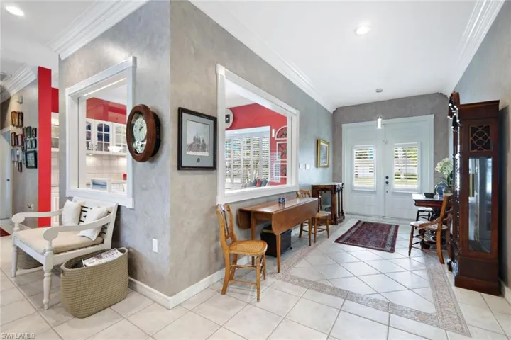 Entrance foyer with light tile patterned floors and crown molding