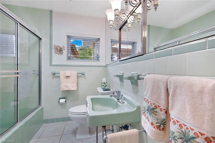 Full bathroom with toilet, tile patterned floors, tasteful backsplash, and tile walls