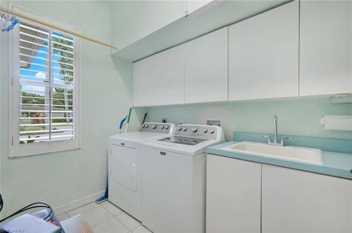 Laundry room featuring washer and clothes dryer, sink, cabinets, and light tile patterned floors
