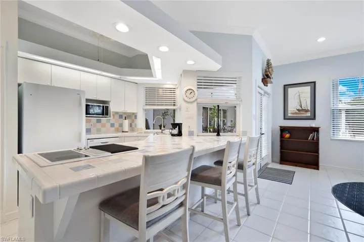 Kitchen with white cabinets, stainless steel microwave, a wealth of natural light, backsplash, and white fridge