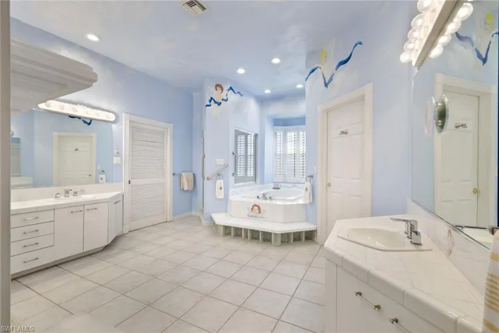 Bathroom with a relaxing tiled tub, vanity, and tile patterned floors