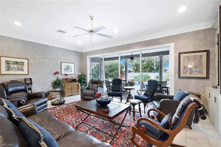Tiled living room featuring ceiling fan and ornamental molding