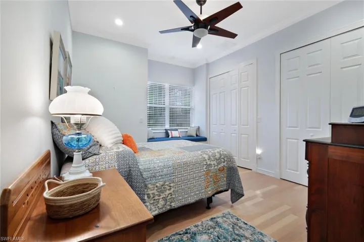 Bedroom with two closets, ceiling fan, hardwood / wood-style floors, and crown molding